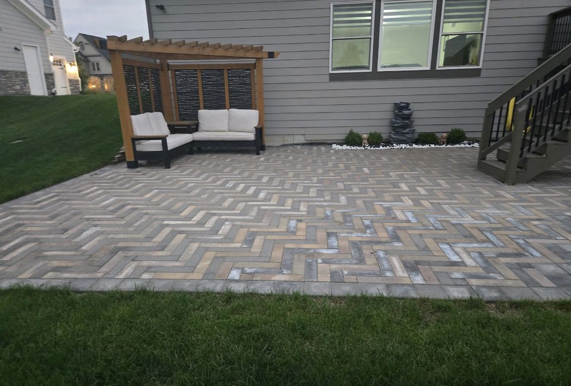 Cedar pergola with privacy screen, outdoor sofa and stacked-slate water feature on the finished patio.